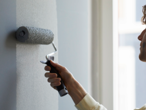 dame som maler med en malerull på veggen inne dame som maler med en malerull på veggen inne