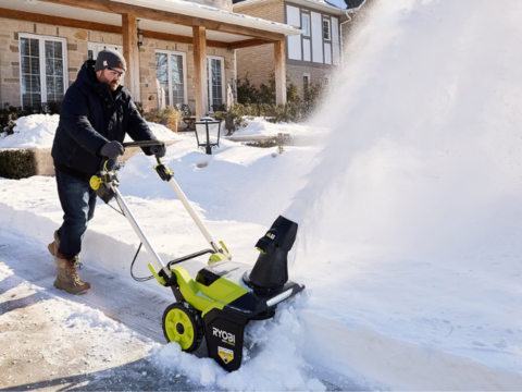 mann med snøfreser fra Ryobi som måker innkjørsel mann med snøfreser fra Ryobi som måker innkjørsel